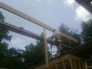 Carpenter setting a ridge beam over a new addition frame — Ice Dam Removal by Roofing Brothers in Glyndon