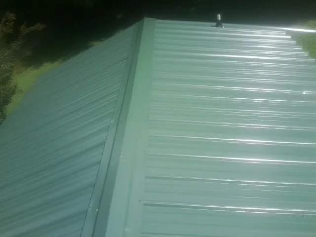 New green metal panels meeting at the ridge of a roof — Flat Roof Repair work by our crew in Glyndon