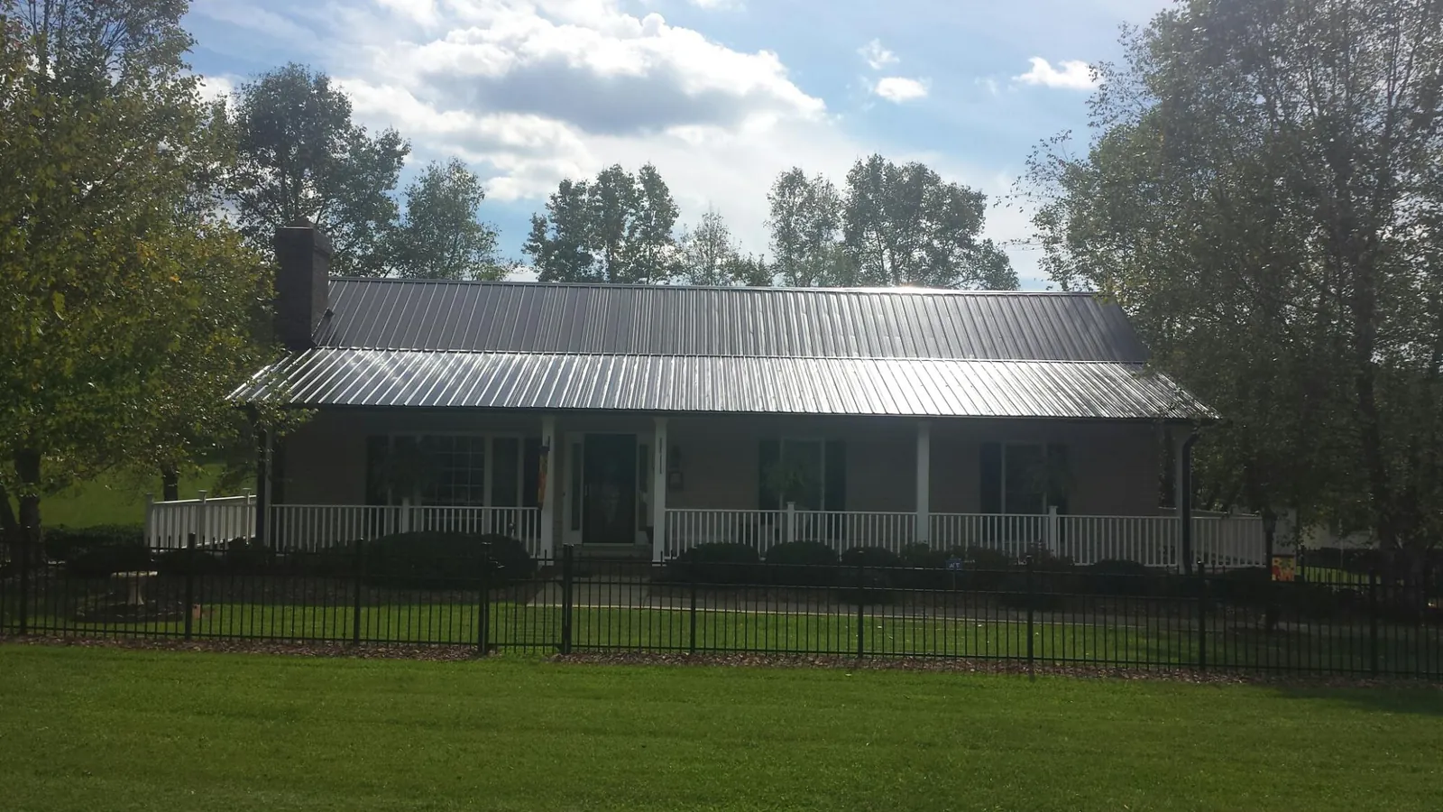 Gray metal roof on a brick ranch with a full width front porch — Gutter Guard Installation work by our crew in Glyndon
