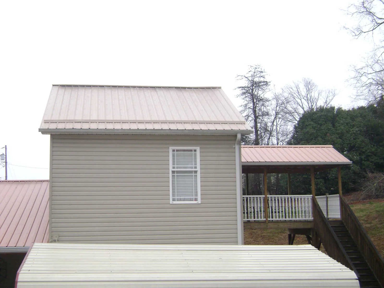 Tan metal roofs on a two story addition and attached porch, from a Roof Replacement job in Glyndon